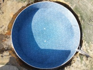 A blue swimming pool with a hole in the ground showcased in a project gallery.