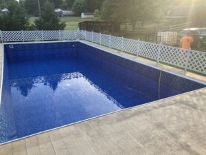 A blue swimming pool with a white fence around it, showcased in our project gallery.