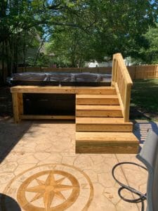 A wooden deck project with stairs and a hot tub.