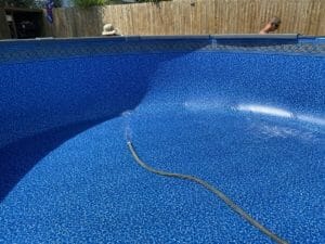 A swimming pool being cleaned with a hose at a project site.