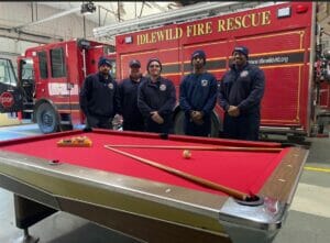 New pool table in firehouse with firemen behind