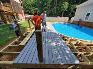 A group of people working on a project on a wooden deck near a pool.