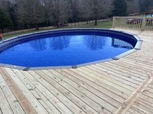 A pool project featuring a wooden deck and a vibrant blue pool.