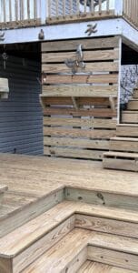 A beautiful wooden deck with stairs, featuring a charming bird perched on the railing.